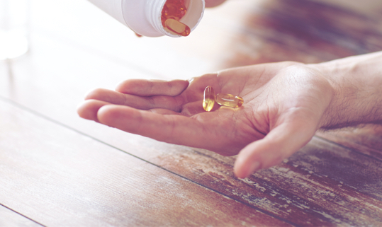 A open handed, palm up, holding a couple medicine capsules