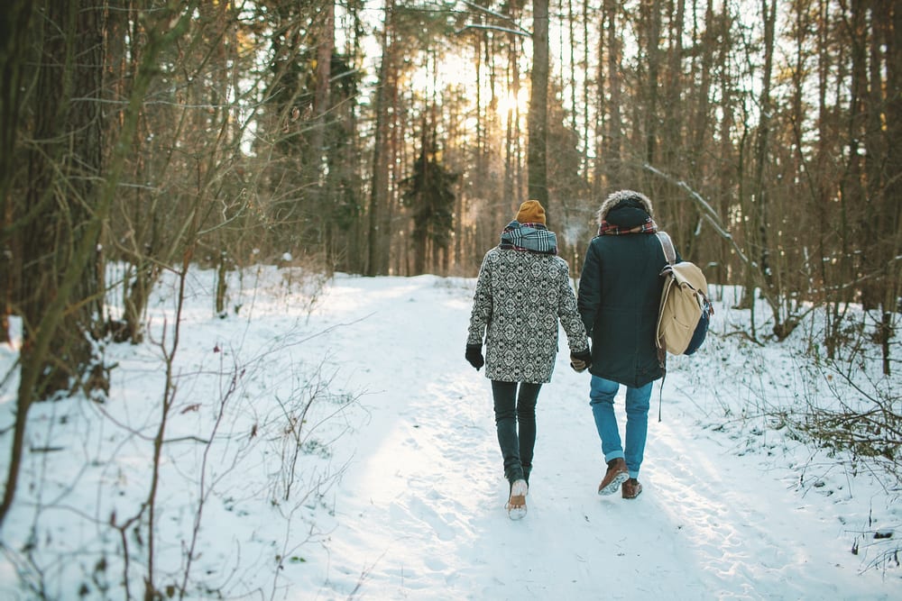 Couple walking in winter through the woods. Did you know walking is the easiest new year's resolution to losing weight? Here's why!