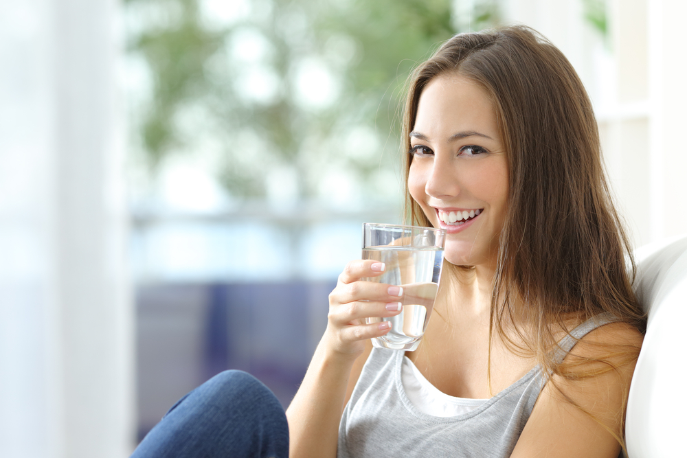 Girl,Drinking,Water,Sitting,On,A,Couch,At,Home,And